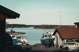 Bootswerft mit aufgebockten Booten außerhalb der Saison, ruhiger See und Waldinseln im Hintergrund, Schweden