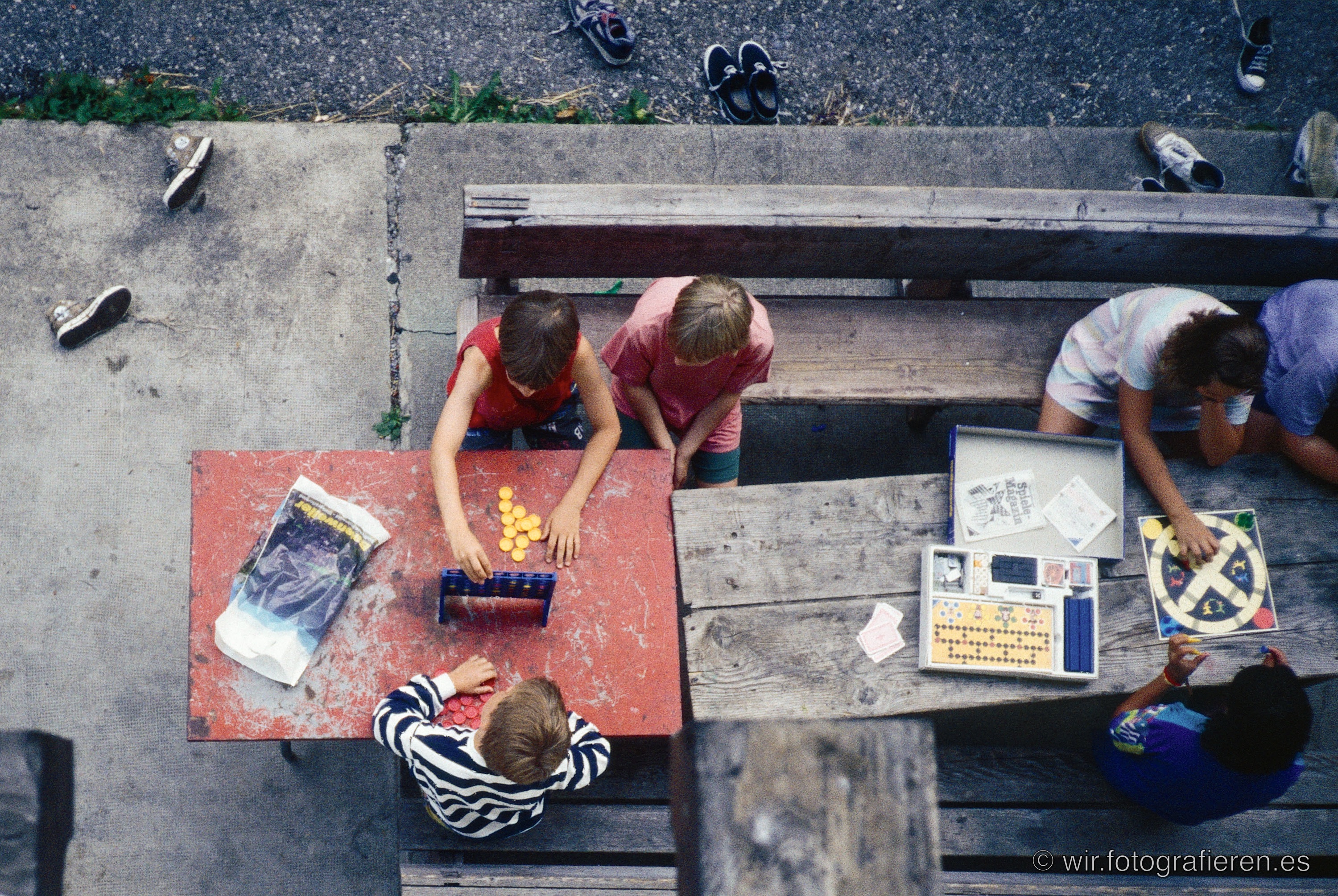 Kinder spielen Brettspiele im Freien von oben fotografiert, Vogelperspektive auf zwei Tische mit Spielen und Chips, Schuhe achtlos auf dem Boden verstreut, analoges Dia aus 1993
